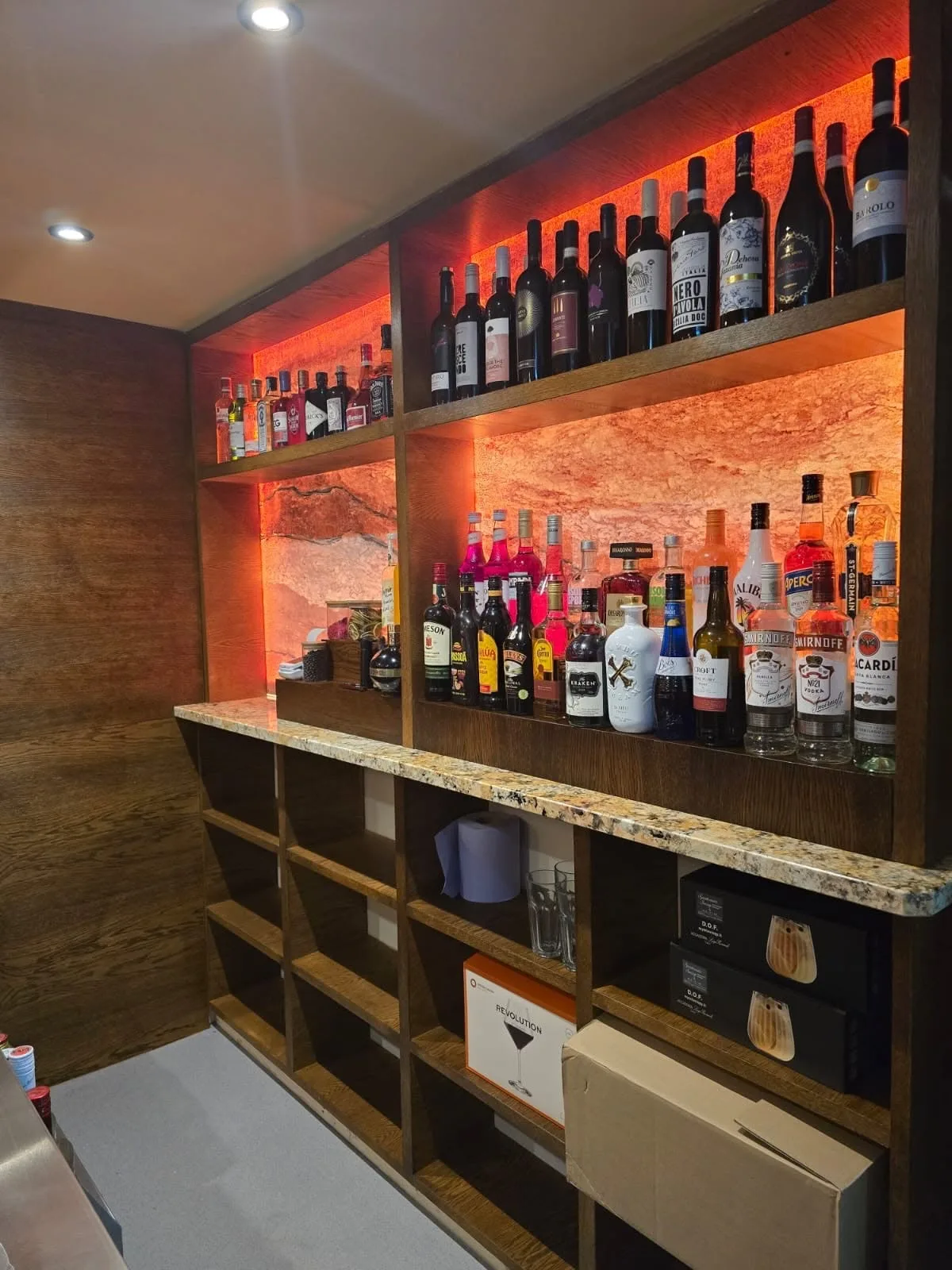 Backlit stone bar shelving stocked with bottles in the new Zarleys function room
